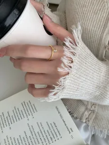 Anello sottile dorato minimalista con zircone su sfondo lifestyle caldo e accogliente