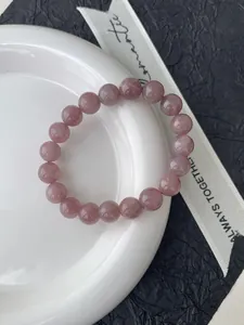 Detailansicht eines polierten grauvioletten Amethyst-Perlenarmband auf weißem Porzellan