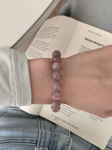 Makroaufnahme von natürlichem brasilianischem Amethyst-Perlenarmband auf Buchseiten