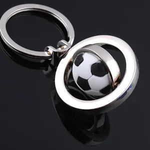 Detalle macro de un llavero de fútbol giratorio de metal sobre un fondo negro pulido