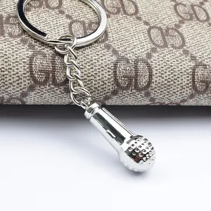 Polished silver metal microphone keychain with chain on premium textured background