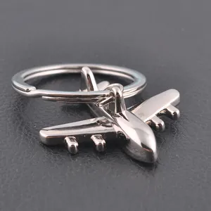 Polished silver metal airplane keychain on black leather background from a 45-degree angle