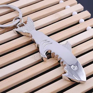 Polished silver metal shark bottle opener keychain on a wooden background