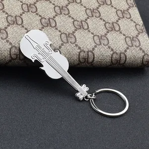 Polished silver metal violin guitar keychain accessory shown on a dark textured background