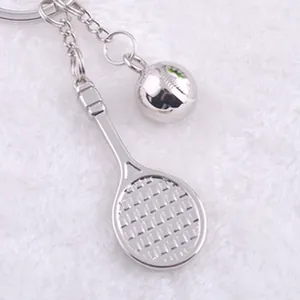 Detailed view of silver metal tennis racket and ball keychain on white soft faux fur