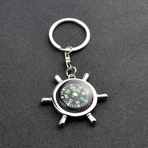 Close-up of a silver ship wheel compass keychain with nautical helm design on grey texture
