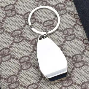 Minimalist silver metal water drop keychain and bottle opener on a premium fabric background