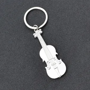 Polished silver metal violin shaped guitar keychain pendant on textured background