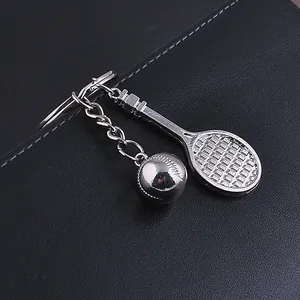 Silver metal tennis racket and ball keychain accessory on black leather background