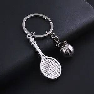 Macro shot of silver metal tennis racket and ball keychain pendants on leather