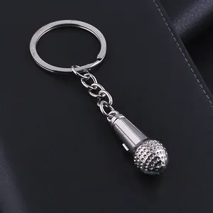 Polished silver metal microphone keychain with round ring and chain on leather surface