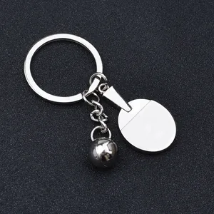Polished silver metal table tennis racket keychain with ball on black background
