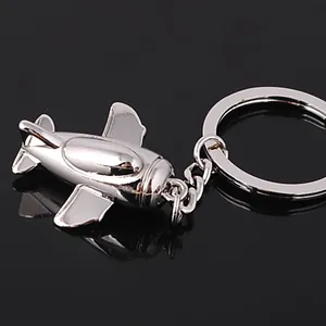 Polished silver metal airplane keychain with minimalist jet model on black background