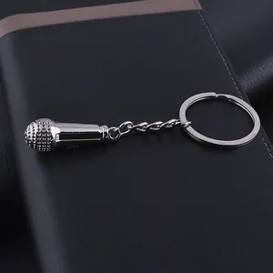 Close-up of a silver microphone keychain made of zinc alloy on a dark leather surface