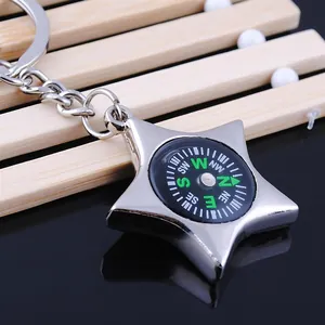 Star-shaped metal keychain with functional compass on light wood background