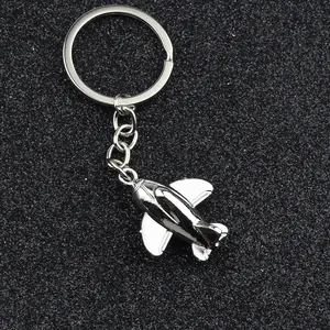 Polished silver metal airplane keychain with aircraft pendant on a black textured background
