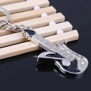Portachiavi a forma di chitarra in metallo con strass su sfondo di legno chiaro