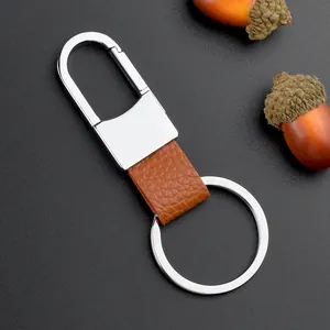 Llavero de metal pulido y cuero marrón sobre fondo oscuro con bellotas decorativas