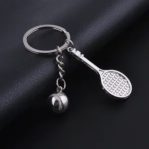 Polished silver metal tennis racket and ball keychain set on black leather background