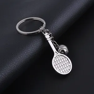 Macro detail of silver tennis racket and ball keychain on black textured leather