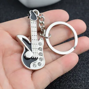 Portachiavi a chitarra in metallo argentato con smalto e strass tenuto in mano per misura