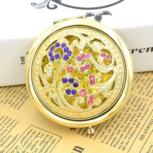 Vintage bronze compact mirror with hollow floral design and purple rhinestones