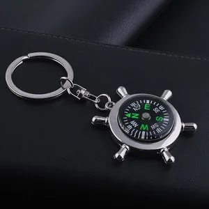 Detail of nautical helm compass keychain in silver metal with green directional markings