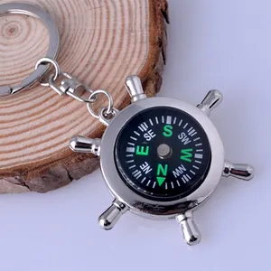 Macro shot of silver metal ship wheel keychain with an integrated black compass dial