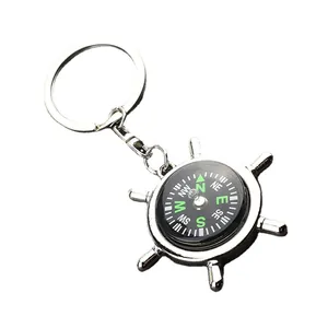 Polished silver metal rudder compass keychain with a classic ship wheel design and white background