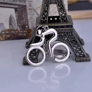 Polished silver metal bicycle keychain with cyclist design on a blue reflective surface