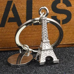 Silver Eiffel Tower metal keychain with round ring and tag on a dark wooden background