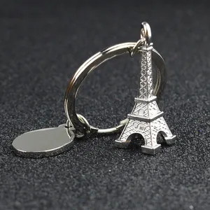 Silver zinc alloy Eiffel Tower keychain with blank oval tag on a black textured surface