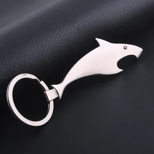 Polished shark-shaped metal keychain bottle opener on black leather surface