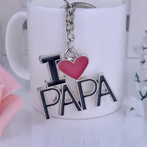 Détail d'un porte-clés métallique I Love Papa sur une tasse avec décor floral