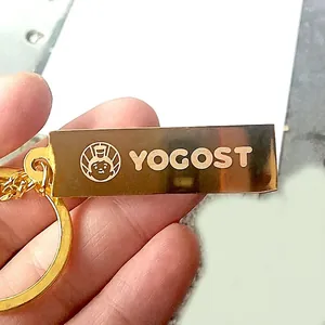 Golden bullion style metal keychain with laser engraved brand logo held by hand
