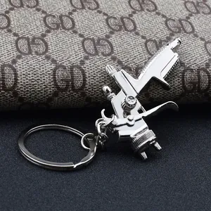 Detailed close-up of a silver spray gun keychain on vintage patterned leather