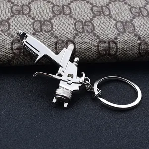 Detailed close-up of a silver metal spray gun shaped keychain with a high-polish finish