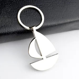Polished silver metal sailboat keychain pendant for car keys on a leather background