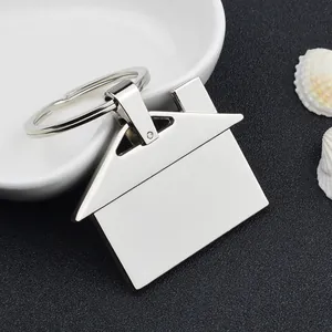 Detailed view of house-shaped metal keychain with polished silver finish on a black surface