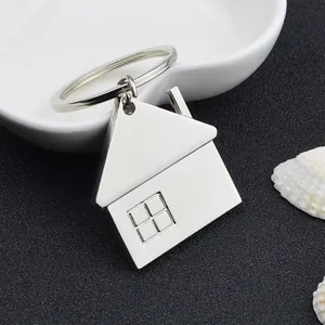 Porte-clés maison en métal argenté poli avec détails de cheminée sur fond noir chic