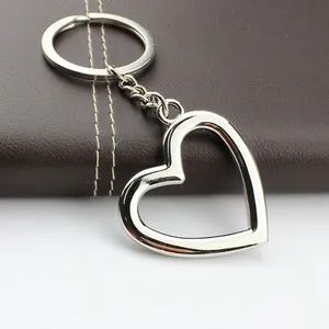 Polished silver hollow heart keychain with metal ring on brown leather background