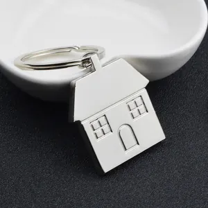 Polished silver house-shaped metal keychain with circular ring on white heart dish