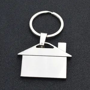 Polished silver metal house keychain with ring on a textured black background