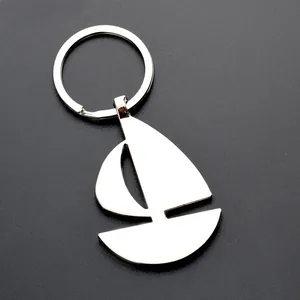 Polished silver metal sailboat keychain with reflective mirror surface on dark background