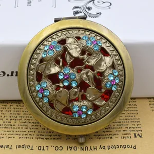 Detailed macro of vintage hollow-out bronze compact mirror with crystal floral design