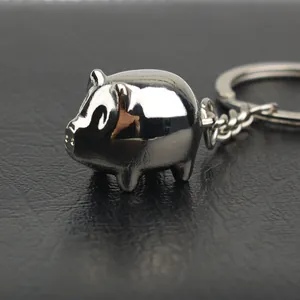 Porte-clés cochon en métal argenté poli avec finition miroir sur fond de cuir noir élégant