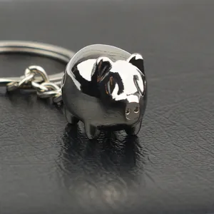 Porte-clés cochon en métal argenté poli au design créatif sur fond de cuir sombre