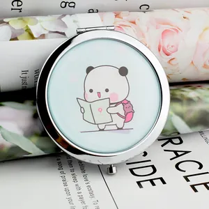 Close-up of a mini silver portable makeup mirror with a cute panda illustration