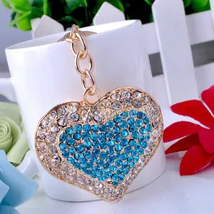 Detail of heart-shaped keychain with blue and white rhinestones on golden chain