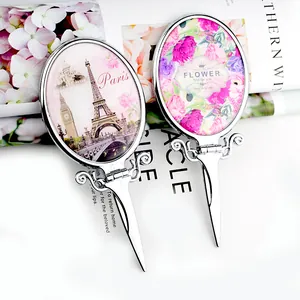 Detail of vintage silver folding handheld mirrors with Eiffel Tower and floral prints